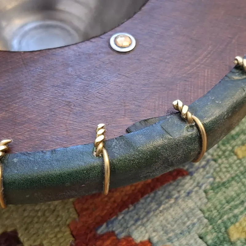 Close view of the round buckler's leather rim laced with brass wire