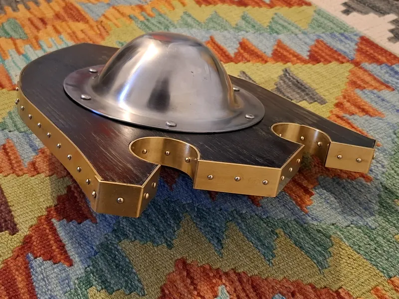 The shaped buckler at an angle, showing the notches and brass edging