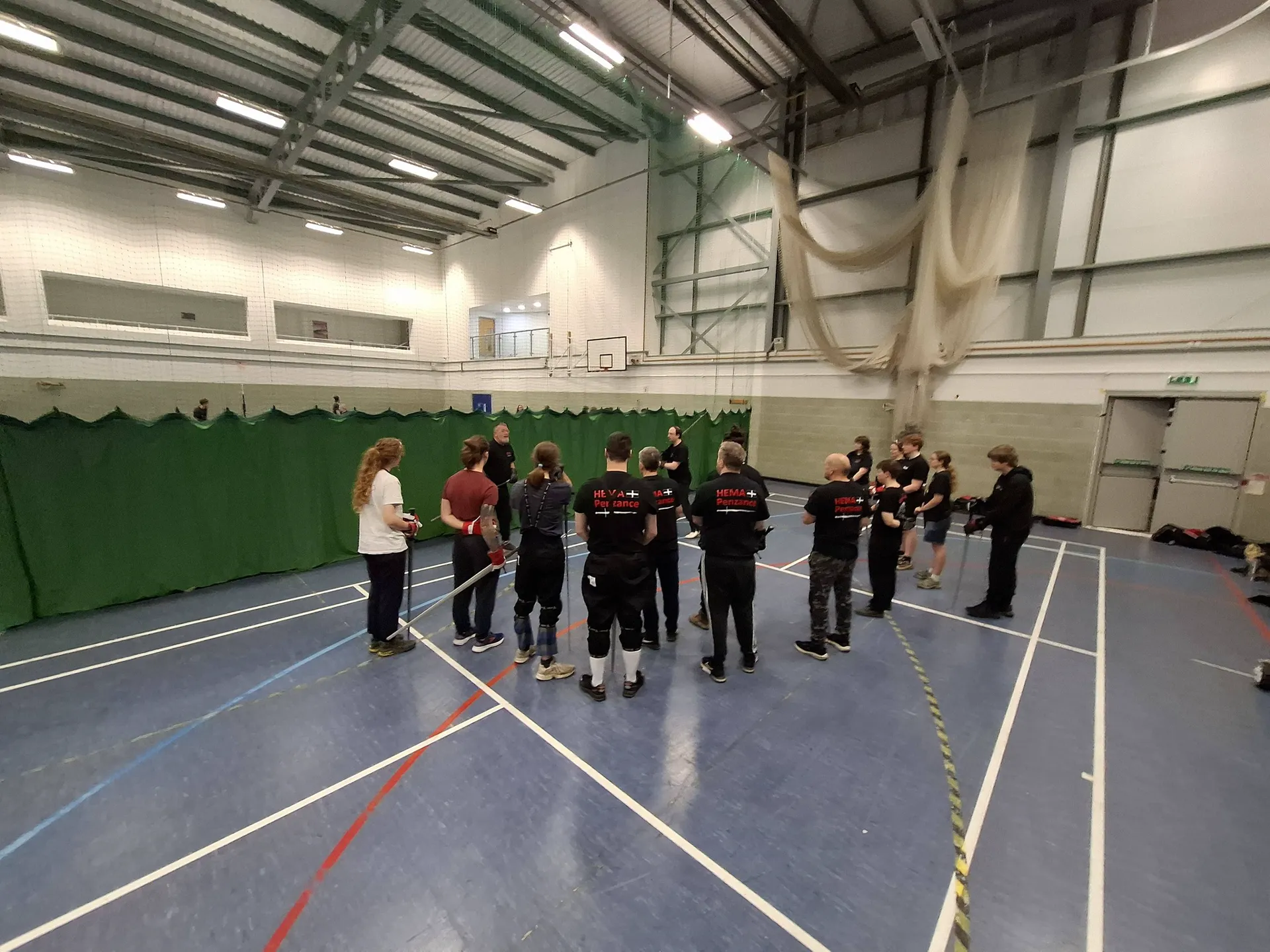 Members of HEMA Penzance gathered in the sports hall at Penzance Leisure Centre, listening to the instructors before training